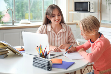 Little boy doing homework with his mother in kitchen