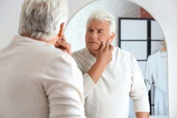 Senior man looking in mirror at home