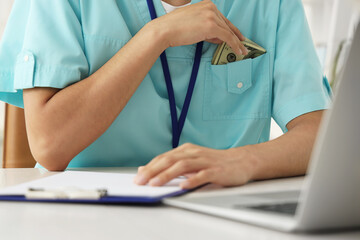 Male Asian doctor with bribe in clinic, closeup