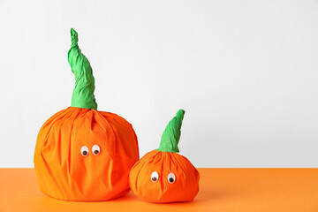 Paper pumpkins for Halloween on orange table