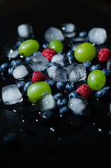 berries with ice cubes on a black background