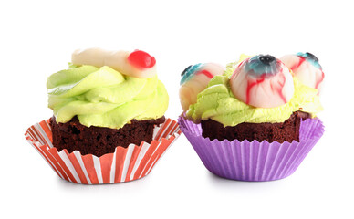 Different delicious Halloween cupcakes with candies on white background
