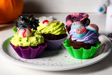 Plate with delicious Halloween cupcakes on light background, closeup