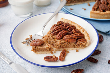 Plate with piece of tasty pecan pie on grey background