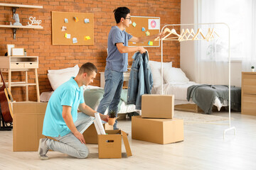 Male students unpacking clothes in dorm room on moving day