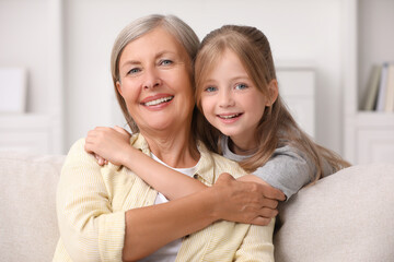 Obraz na płótnie Canvas Happy grandmother hugging her granddaughter at home