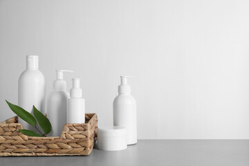 Different cosmetic products and leaves on grey table. Space for text