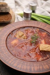 Bowl of delicious borscht on table, closeup.