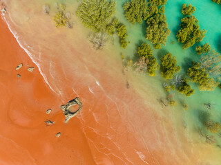 Aerial view of red sandy coastline along turquoise water at Red Sand Beach, Roebuck Bay, Broome, Western Australia