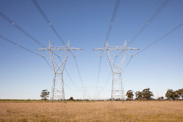 Tall High-Voltage Pylons Amidst Expansive Grasslands