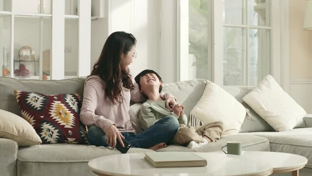 young asian mother and five-year-old son having a conversation sitting on family couch at home