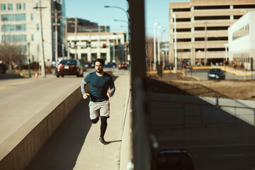Young man jogging and exercising on a sidewalk on a bridge in the city