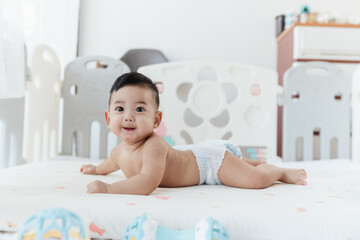 Happy Asian baby start to crawling on a bed at home, Adorable development 5 months old. Baby healthcare hygiene concept.