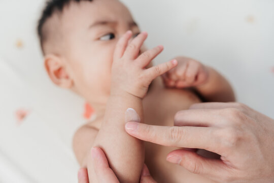 Tender Motherhood , Mother’s Finger Applying Skin Care Lotion on Her Son’s Arm in Closeup Shot, Embracing the Concept of Baby Care.