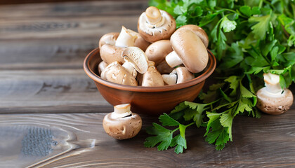 Fresh mushrooms in a clay bowl and parsley on a dark rustic wooden table. Vegetarian food is on the table.