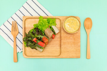 close up salad mixed tuna crab pork vegetable roll in noodle tube on Chopping board green background.