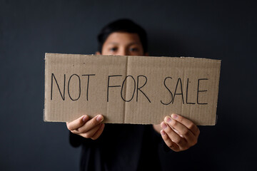 Human trafficking and stop child abuse campaign. Kid showing cardboard with text not for sale. 
