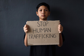 Asian kid holding cardboard with text message Stop Human Trafficking. Human trafficking awareness...