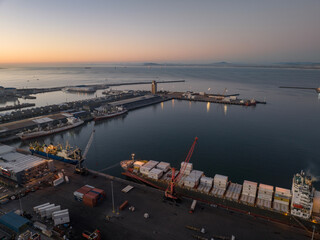 Dusk view of the Cape Town commercial port and container ships waiting to complete loading and...