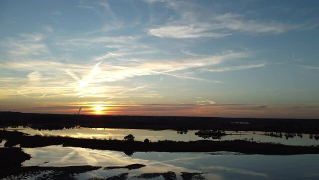 A drone rises over a silhouetted horizon in the calm waters of Mechels Broek.