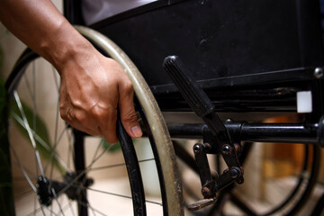 Obraz premium Unrecognizable disabled man sitting in a wheelchair. Recovery and healthcare concepts.