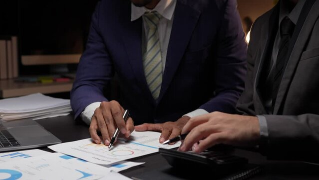 Teamwork of Asian business people discussing and calculating with a calculator on evaluation data in a conference room. with the growth and pointing to the chart graph financial account.