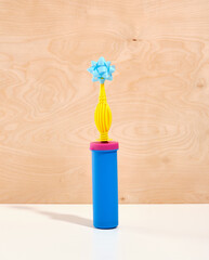 The balloon air pump stands vertically on a wooden background. A blue celebrate gift bow is attached to the air pump.