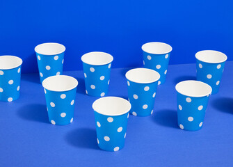 Lots of brightly colored paper cups for holiday drinks and cocktails on a blue background. Birthday party.