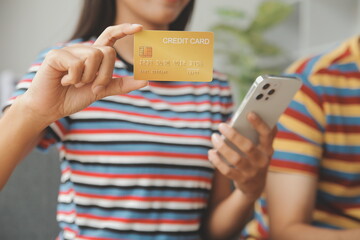 .Young couple use credit card for online shopping on internet website at home. Number on the credit card is mock up. No personal information shown on the credit card. Online business shopping concept.