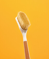 Wooden eco friendly brush with a natural bristle for cleaning and scrubbing in yellow background....