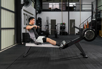 Fitness-conscious man passionately engaging in indoor rowing, in well-equipped gym