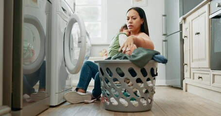Laundry, home and mother holding her baby while spring cleaning in the kitchen of her apartment. Upset, housekeeping and moody young mom washing clothes with her toddler child in their modern house. - Powered by Adobe