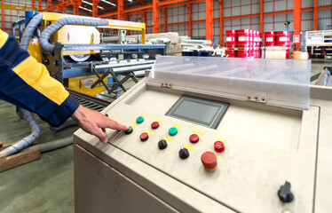 Industrious worker meticulously operating complex machinery within a bustling manufacturing plant.
