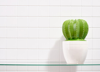 A beautiful statuette of a green cactus in a white pot. Copy space for text.