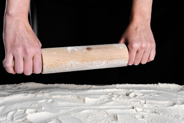 Baker hands with rolling pin above flour. Baking concept.