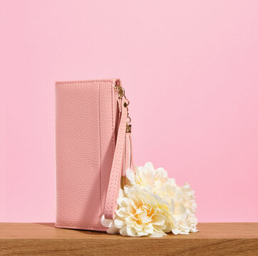 A beautiful pink wallet for money or business cards with flowers on a pink background. Copy space for text.