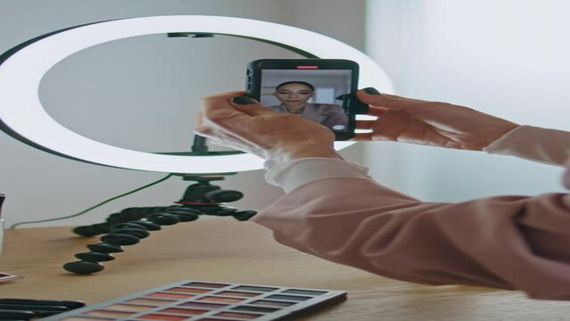 Closeup influencer adjusting smartphone tripod at home. Girl streaming vertical