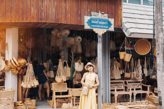 Young asian woman traveler in dress with hat traveling to wicker shop on Chang Moi Kao Road, Tourist visit at the old city in Chang Mai, Thailand. Asia Travel, Vacation and summer holiday concept