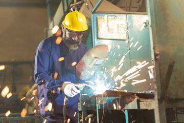 welder wearing protective hat, eyeglasses while working at factory - obrazy, fototapety, plakaty