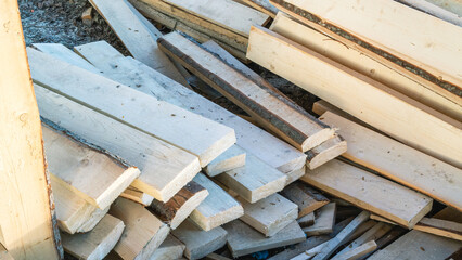 Sawn boards for construction work. New boards made of light wood. Longitudinal sawing of logs from various types of wood using a woodworking machine. Lumber on the sawmill.