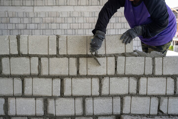 Fototapeta na wymiar a worker erects a wall of aerated concrete blocks.