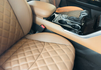 Modern luxury car brown leather interior. Part of orange leather car seat details with white stitching. Interior of prestige car. Comfortable perforated leather seats. Perforated leather.