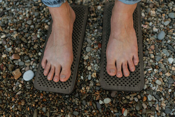 Sea Woman feet stepping on sadhu board during indian practice on the seashore. . Healthy lifestyle concept. tool for working out your inner state