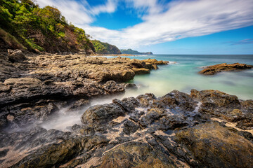 Long exposure, pacific ocean waves on rock in Playa Ocotal, El Coco Costa Rica. Famous snorkel beach. Picturesque paradise tropical landscape. Pura Vida concept, travel to exotic tropical country.