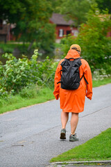 Person walking in a orange raincoat near Black river Orebro Sweden