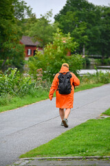 Person walking in a orange raincoat near Black river Orebro Sweden