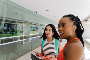 Students looking away with expression of surprise in the face standing on a modern campus