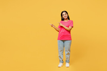 Full body young happy Indian woman wearing pink t-shirt casual clothes point indicate on workspace...