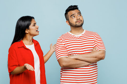 Young displeased sad couple two friends family Indian man woman wear red casual clothes t-shirts together scream, arguing ignoring look aside isolated on pastel plain light blue cyan color background