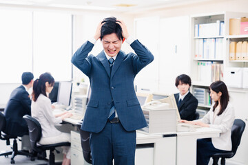 オフィスで頭を抱える若いビジネスマン